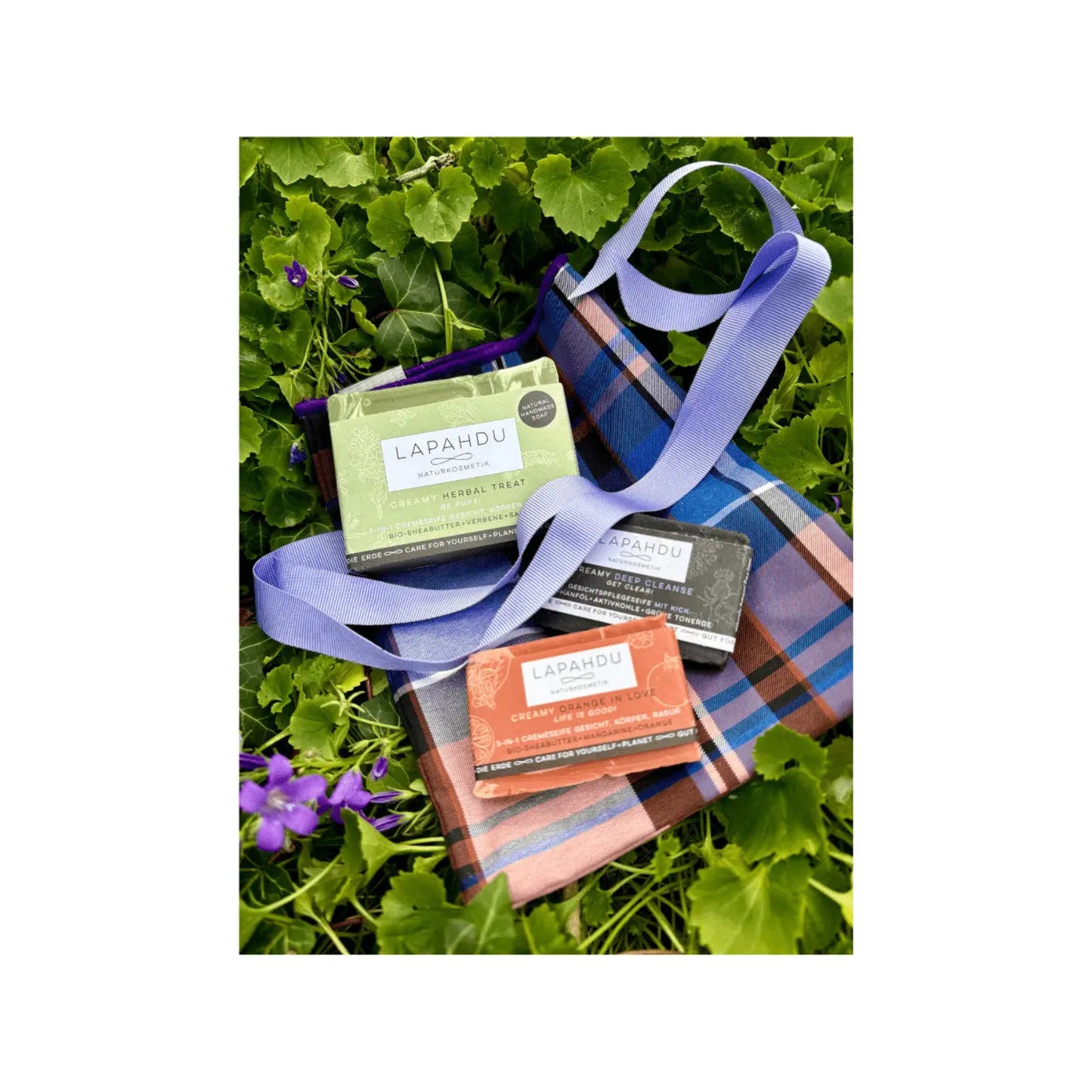 Geschenkset-mit-3-handgemachten-naturseifen-von-lapahdu-naturkosmetik-hübsch-und-nachhaltig-verpackt- in einem blau-lila-karierten-stoffsäckchen mit lila schleife-das-perfekte-geschenk